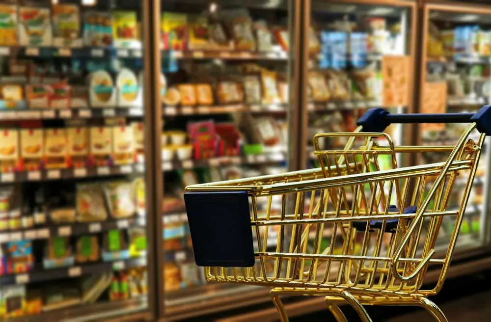 A shopping trolley in front of stocked supermarket shelves